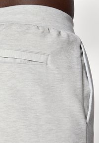 Lys grå sweatpants med en glat bomuldsblanding, elastisk talje og en diskret baglomme til opbevaring.