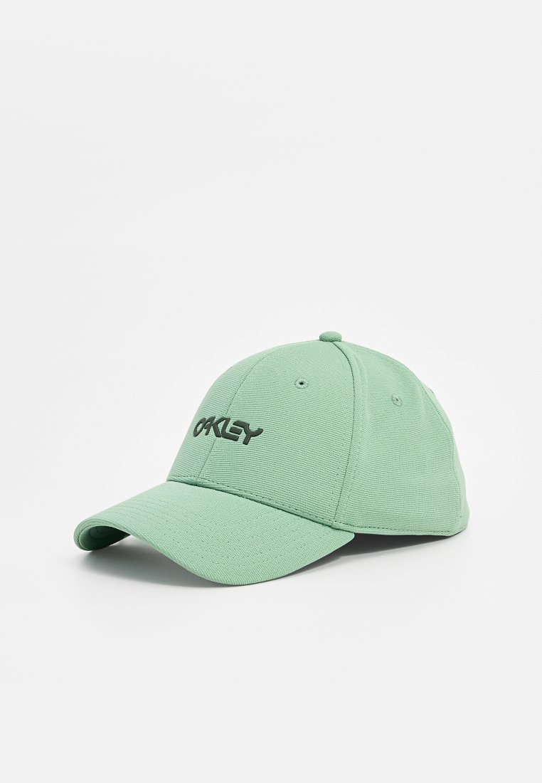 Zielona czapka wykonana z teksturowanej tkaniny z wygiętym daszkiem i przeszyciami. Na przedniej części znajduje się czarne logo "Oakley".