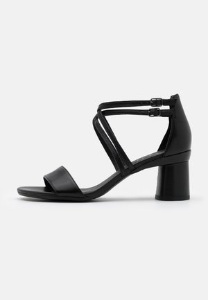 Czarne skórzane sandały na obcasie z otwartym noskiem, szerokim paskiem z przodu, krzyżującymi się paskami wokół kostki oraz blokowym obcasem.