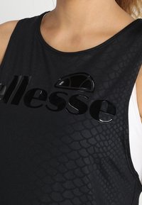 Czarny top bez rękawów z błyszczącym logo i fakturą przypominającą łuski; posiada okrągły dekolt i bezrękawowy krój.