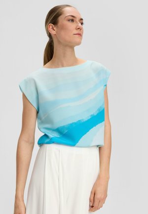 T-shirt à manches courtes en tissu léger avec un motif dégradé de nuances de bleu clair à bleu profond. Encolure ronde et coupe ample. Associé à un pantalon blanc.