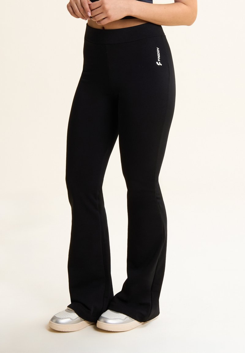 Pantalones deportivos negros de campana hechos de material elástico, con una cinturilla alta y un logo blanco en el lateral. Textura suave sin patrones.