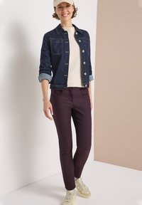 Jeansjakke med en struktureret pasform, lyseblå manchetter, cremet striktrøje og maroon slim-fit bukser, parret med beige sneakers.