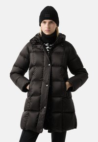 Černý péřový kabát se zapínáním na zip, kovovými druky a kapucí. Nositelný přes černobílý pletený svetr a v kombinaci s černou čepicí.