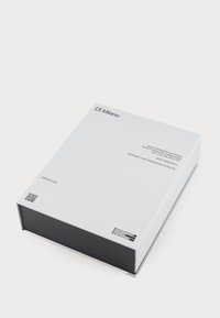 Weißer rechteckiger Kasten mit schwarzem Boden, der schwarzen Text und QR-Codes auf dem Deckel zeigt. Minimalistisches Design mit schlanken, klaren Linien.