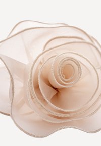 Bežna čipkasta ruža s višeslojnim, lepršavim laticama koje imaju mekan, prozračan tekstur i delicatno prošivene detalje uz rubove.