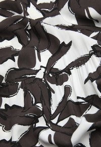 Zwart en bruin abstract patroon op witte stof, met een gladde textuur en geplooide details. Het ontwerp bevat golvende organische vormen.
