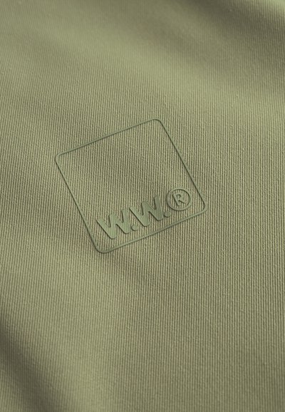 Žalia tekstūruota medžiaga su iškeltu logotipu, kuriame yra „W.W.“ kvadrate. Medžiaga turi smulkų, vertikalų briaunavimą.