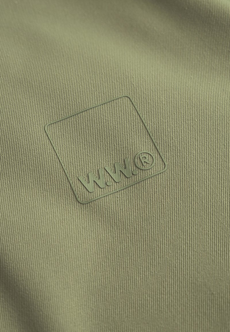 Tejido verde texturizado con un logo en relieve que contiene "W.W." dentro de un cuadrado. El material presenta un fino estriado vertical.