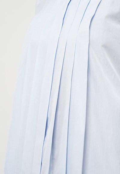 Svijetloplava košulja s vertikalnim nabranjima, glatkom teksturom i čistim, minimalističkim dizajnom s suptilnim detaljima šivanja.
