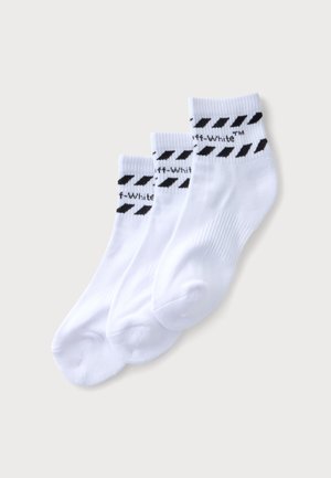 Trois paires de chaussettes blanches aux chevilles avec des rayures diagonales noires et un texte partiel "Off-White" près de la bordure supérieure, sur un fond clair uni.
