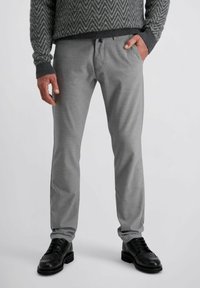 Graue Hosen mit einer glatten Textur, geradem Schnitt und subtilen Designdetails, kombiniert mit schwarzen Lederschuhen mit dekorativen Perforationen.