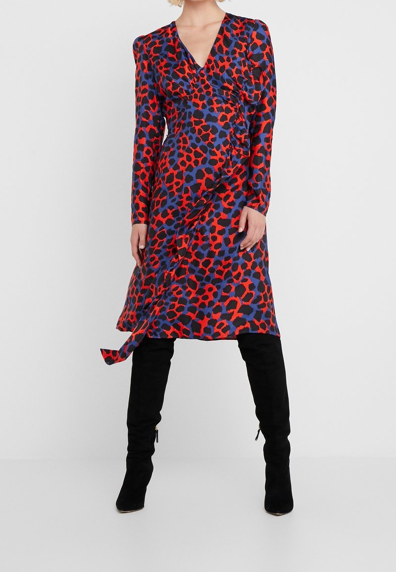 Röd och blå leopardmönstrad klänning med långa ärmar, V-ringning och drapering på sidan. Matchad med knähöga svarta stövlar.