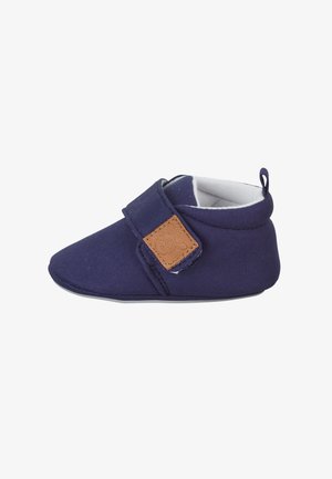 Marineblaue Stoffschuhe mit weicher Textur, abgerundeter Zehenpartie und verstellbarem Klettverschluss, der mit einem braunen Akzentpatch versehen ist. Flaches Design.