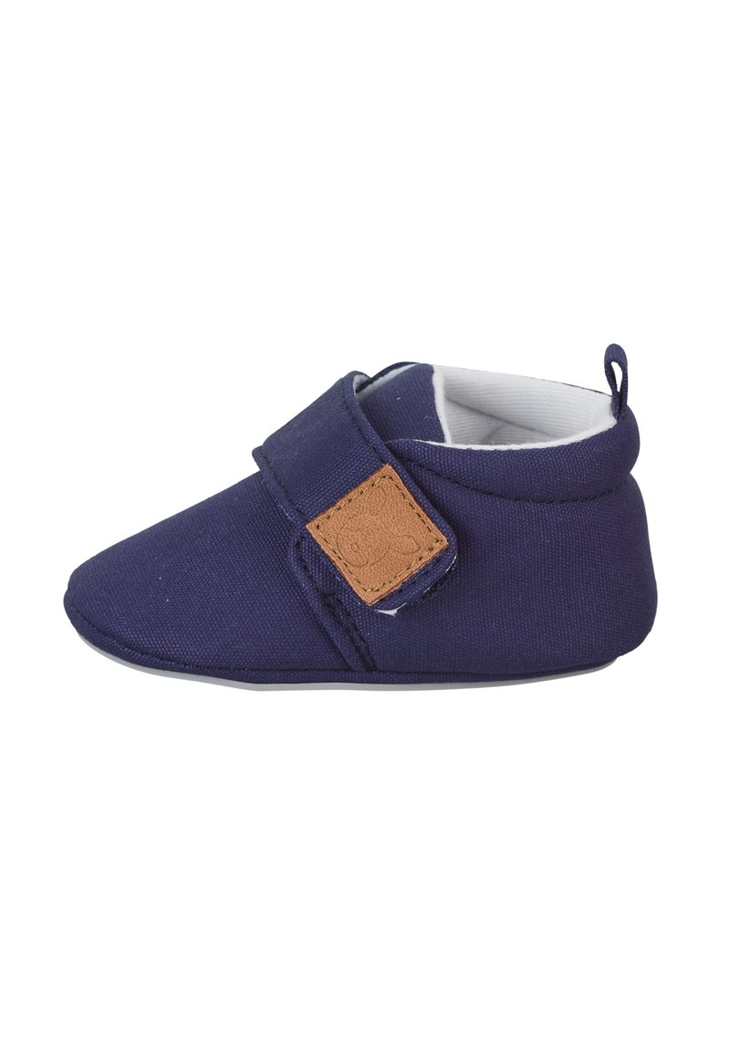 Navy blue fabric shoe with a soft texture, rounded toe, and adjustable Velcro strap featuring a brown accent patch. Low-profile design.