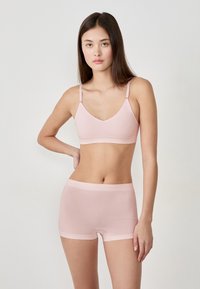 Bralette rose clair sans couture avec bretelles ajustables et shorty assorti. Tissu doux et élastique, texture lisse et design minimal.