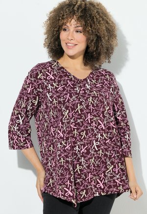 Haut bordeaux à manches 3/4 présentant un motif de rubans colorés en rose et beige. Design en V et silhouette ample.