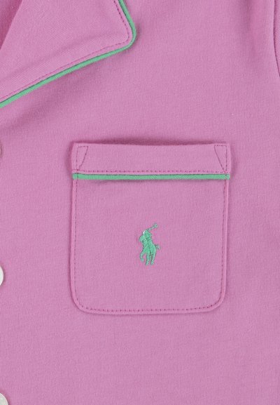 Rosa skjorta med en ficka med grön kant och en broderad grön polo-spelare-logotyp. Slät textur med knappstängning.