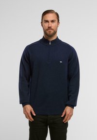 Marinefarbener Pullover mit hohem Kragen, Reißverschluss und langen Ärmeln. Mit einem kleinen Logo auf der Brust sowie gerippten Bündchen und Saum.