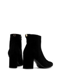 Czarne zamszowe botki za kostkę na grubej obcasie, z bocznym zamkiem błyskawicznym i złotym akcentem na obcasie. Gładka tekstura, klasyczna sylwetka.