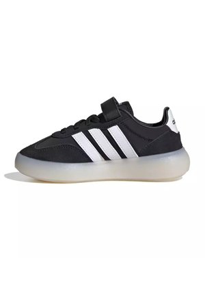 Scarpa da ginnastica Adidas bianca e nera con tre strisce bianche, lacci e chiusura in velcro e suola spessa traslucida, vista lateralmente.