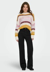 Strickpullover mit mehrfarbigen Streifen in Gelb-, Rosa- und Burgundertönen. Verkürztes Design mit weiten Ärmeln, kombiniert mit schwarzen weiten Hosen.