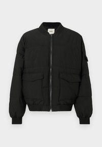 Schwarze Steppjacke mit hohem Kragen, Frontreißverschluss, zwei großen Taschen mit Klappen und gerippten Bündchen, gefertigt aus einem glatten, strapazierfähigen Material.