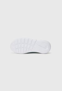 Weiße Sneaker-Sohle mit strukturiertem Grip-Muster, abgerundetem Absatz und Zwischensohlen-Details. Glatte Oberfläche mit Logoprint in der Nähe des Absatzes.