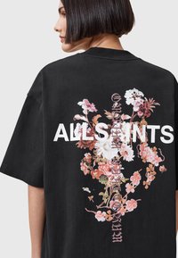 T-shirt oversize nera con una grafica floreale stampata sul retro e il testo bold bianco "ALLSAINTS". Materiale in cotone morbido e vestibilità rilassata.