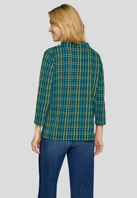 Bunt kariertes Oberteil in Blau, Grün und Schwarz, mit Dreiviertelärmeln und geradem Schnitt. Leichter, strukturierter Stoff.