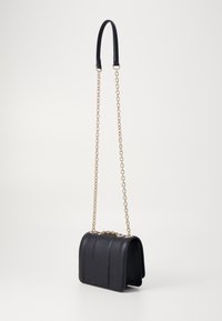 Schwarze Lederhandtasche mit strukturiertem Design, ausgestattet mit einem Kettenriemen und einer glatten Oberfläche. Mit vertikalen Nähten und einem goldenen Verschluss verziert.