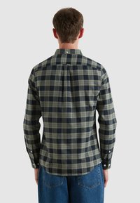 Groen en marineblauw geblokt overhemd met een button-down kraag, lange mouwen en een afgeronde zoom. Bevat witte knopen op de manchetten en een detail op de achterkant.
