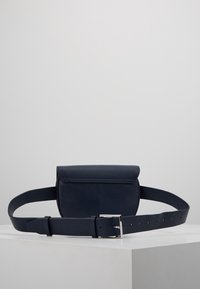 Granatowa skórzana saszetka na pasku z klapą na zakładkę, regulowanym paskiem i srebrną klamrą. Gładka faktura i prosty, prostokątny kształt.