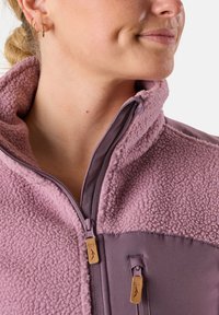 Fleecejacke in lichtpaars met een hoge kraag, een ritssluiting aan de voorkant en contrasterende gladde stof op de schouders. Voorzien van dubbele ritssluitingen met leren accenten.