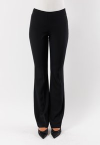 Pantaloni neri sartoriali con design a gamba dritta e texture liscia. Presentano un frontale piatto e una vita classica. Indossati con tacchi neri appuntiti.