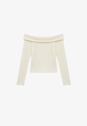 Top de hombros caídos y manga larga en tela texturizada color crema con patrón ondulado y dobladillo con volantes en los puños y la parte inferior.