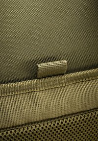 Olive zeleno teksturirano blago s gladkim trakom in mrežnim delom; vsebuje šivljenje in majhno zanko za pritrditev.