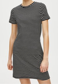 Schwarz-weißer gestreifter Kurzarmkleid mit Rundhalsausschnitt und figurbetonter Form. Der Stoff scheint weich und leicht dehnbar zu sein.