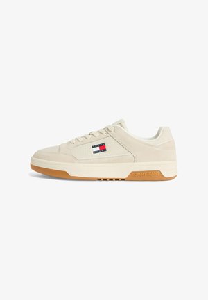 Beige low-top sneaker with lace-up design, gum sole, and Tommy Jeans logo on side and sole.