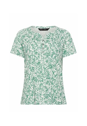 Blouse blanche à manches courtes avec motif abstrait de feuilles vertes et patte de boutonnage à quatre boutons au niveau de l'encolure.