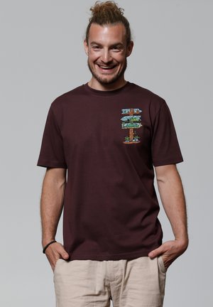 Bordeauxkleurige katoenen t-shirt met korte mouwen, voorzien van een kleurrafische afbeelding van richtingborden en natuurscenes op het linkerborstgebied.