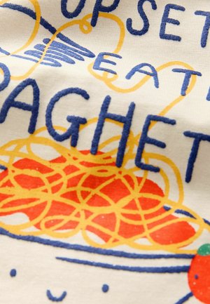 Material din bumbac brodat, cu o ilustrație colorată de spaghetti în galben și roșu, însoțită de un text îndrăzneț albastru care spune "SUPĂRAT MÂNCÂND SPAGHETTI."