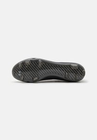 Sole di scarpini da calcio neri con un design in fibra di carbonio testurizzata, dotata di sei tacchetti trasparenti e un bordo curvato per un miglior grip.