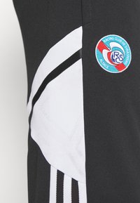 Schwarze Sportshorts mit weißen und schwarzen Seitenpaneelen, die ein strukturiertes Design aufweisen und ein kreisförmiges gesticktes Logo in Blau und Rot haben.