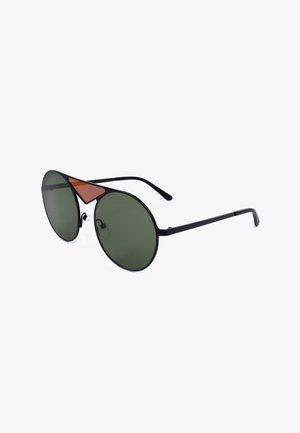 Occhiali da sole aviator in metallo nero con lenti rotonde verde scuro e un piccolo dettaglio triangolare marrone sul ponte.