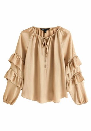 Beige blouse van lichte stof met een ronde halslijn, strikdetail en lange mouwen met gelaagde franjerand. Sluiting met toggleknop.