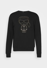 Sudadera negra de mangas largas con un contorno dorado de un personaje de dibujos animados en un traje, con gafas de sol y un diseño de coleta en el frente.