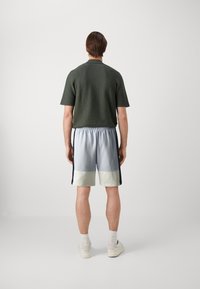 Pull vert à manches courtes avec une finition texturée, associé à un short de sport bleu clair, menthe et marine doté d'une taille élastique.