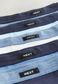 Drei Paare Boxershorts in Marineblau, Hellblau und Weiß, mit elastischen Taillenbändern und schwarzen "NEXT"-Labels. Weiches Material und verschiedene Texturen.
