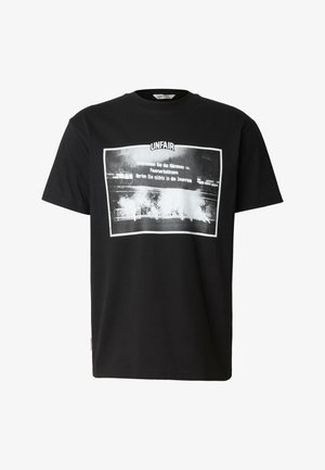T-shirt nero a maniche corte con una grafica rettangolare bianca raffigurante una scena fumosa di uno stadio e testo in tedesco sotto la parola "UNFAIR."